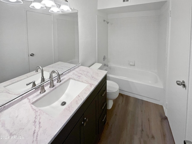 full bathroom with toilet, tiled shower / bath combo, vanity, and wood-type flooring