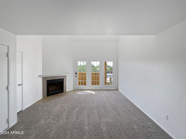 unfurnished living room with a tile fireplace and light carpet