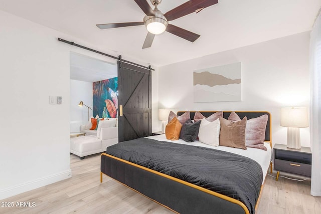 8437 E Bonnie Rose Ave, Scottsdale, AZ 85250 - bedroom with a barn door, wood finished floors, a ceiling fan, and baseboards