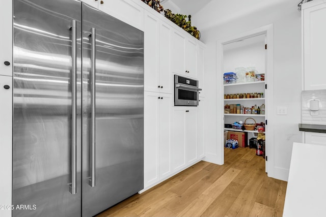 908 W Caldwell St, Phoenix, AZ 85041 - kitchen featuring light wood-style floors, white cabinets, appliances with stainless steel finishes, dark countertops, and backsplash