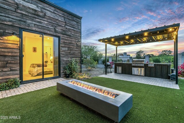 908 W Caldwell St, Phoenix, AZ 85041 - yard at dusk featuring exterior kitchen, a pergola, a patio area, an outdoor fire pit, and fence