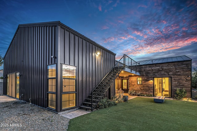 908 W Caldwell St, Phoenix, AZ 85041 - back of property at dusk featuring a yard, stairway, and stone siding