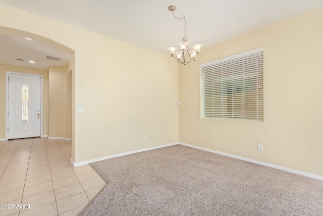 tiled spare room with a chandelier