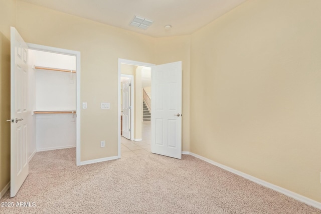 unfurnished bedroom with light colored carpet, a closet, and a walk in closet