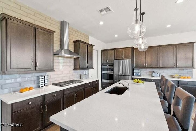 11249 N Blakely St, Surprise, AZ 85388 - kitchen with wall chimney exhaust hood, stainless steel appliances, a sink, backsplash, and a kitchen breakfast bar