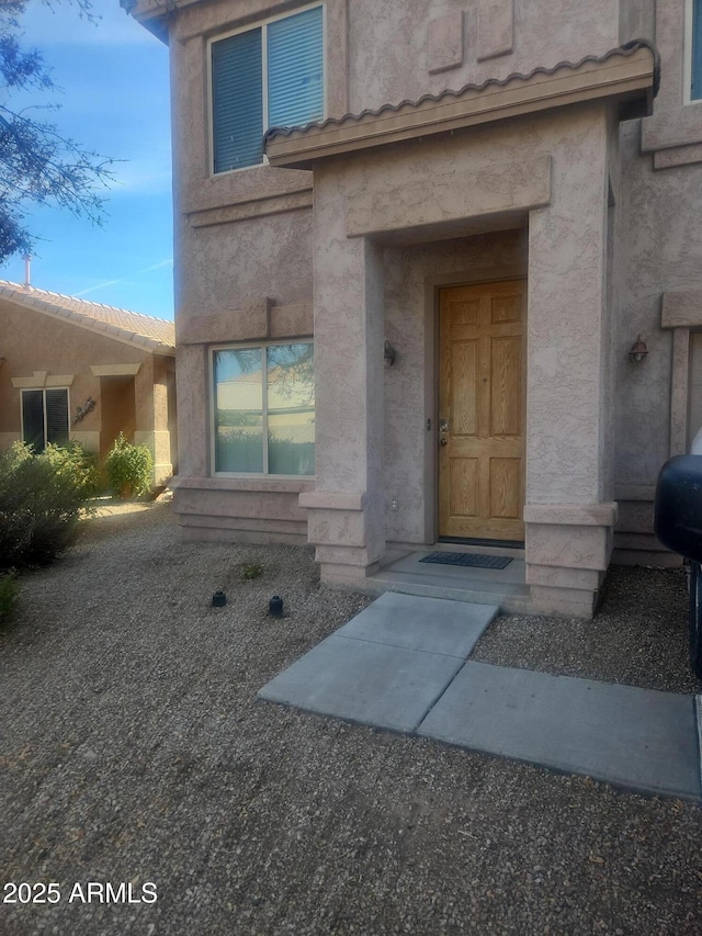 doorway to property featuring a tile roof and stucco siding