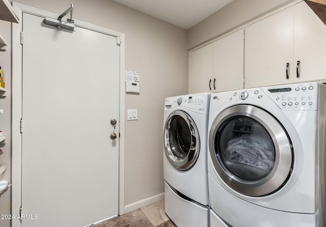 clothes washing area with washer and clothes dryer and cabinets