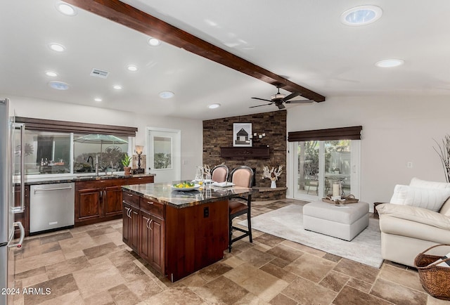 kitchen featuring appliances with stainless steel finishes, a breakfast bar, ceiling fan, lofted ceiling with beams, and a center island