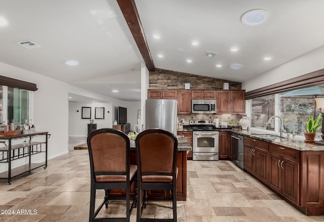 kitchen with backsplash, sink, vaulted ceiling with beams, appliances with stainless steel finishes, and light stone counters