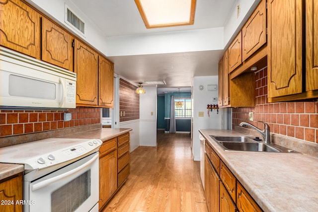 kitchen featuring decorative backsplash, white appliances, light hardwood / wood-style flooring, and sink