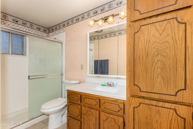 bathroom with tile patterned floors, a shower with door, vanity, and toilet