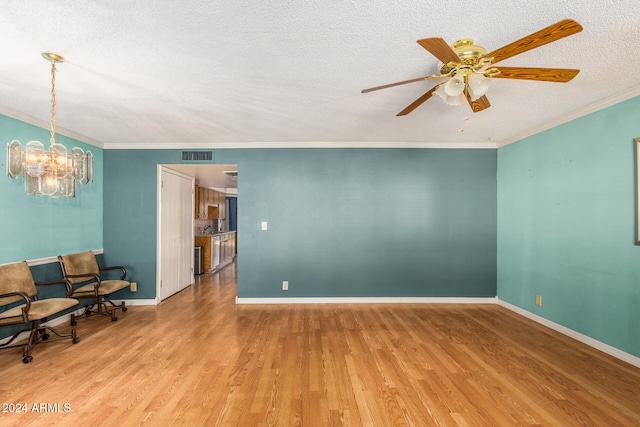 spare room with ceiling fan with notable chandelier, crown molding, light wood-type flooring, and a textured ceiling