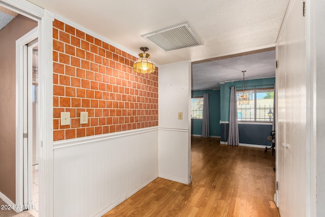 corridor with wood-type flooring and a textured ceiling