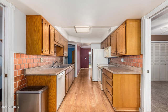 kitchen with light wood-type flooring, white appliances, backsplash, and sink