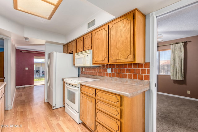 kitchen featuring tasteful backsplash, white appliances, and light wood-type flooring