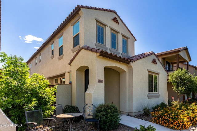 mediterranean / spanish house featuring a tiled roof and stucco siding