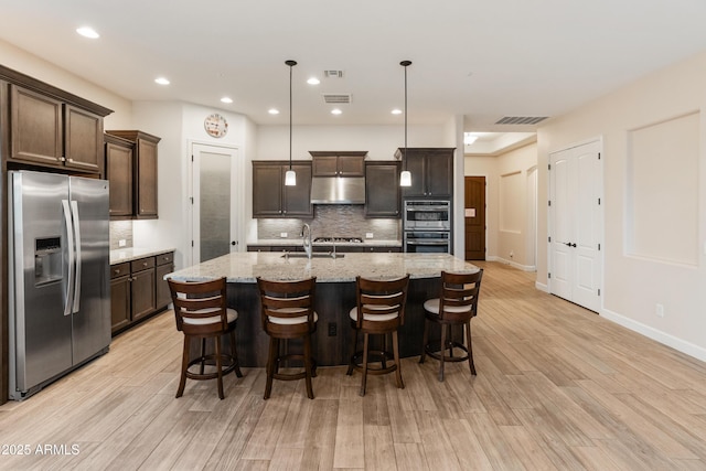 31207 N 124th Dr, Peoria, AZ 85383 - kitchen featuring appliances with stainless steel finishes, under cabinet range hood, dark brown cabinetry, tasteful backsplash, and light wood-style floors