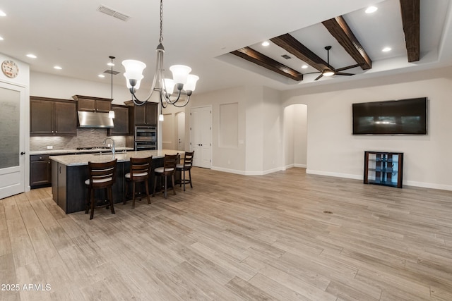 31207 N 124th Dr, Peoria, AZ 85383 - kitchen featuring arched walkways, decorative backsplash, a breakfast bar, dark brown cabinets, and a chandelier