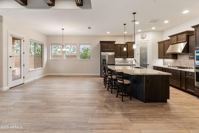 31207 N 124th Dr, Peoria, AZ 85383 - kitchen featuring appliances with stainless steel finishes, a sink, under cabinet range hood, a chandelier, and light wood-style flooring