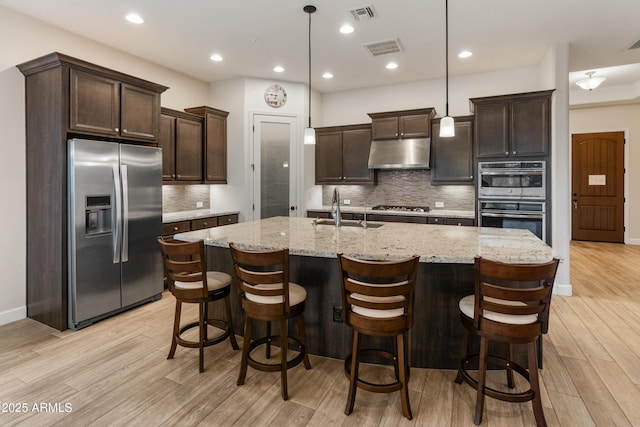 31207 N 124th Dr, Peoria, AZ 85383 - kitchen with stainless steel appliances, a sink, under cabinet range hood, dark brown cabinetry, and light wood-type flooring