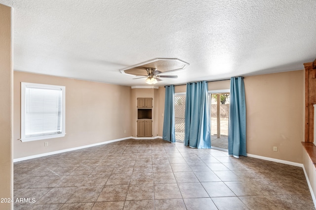 empty room featuring light tile patterned floors, a textured ceiling, and ceiling fan