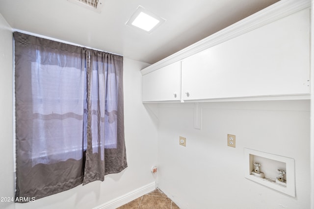 washroom featuring hookup for a washing machine, cabinets, and light tile patterned floors