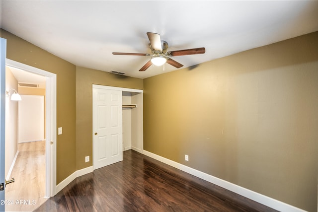 unfurnished bedroom with ceiling fan, dark wood-type flooring, and a closet