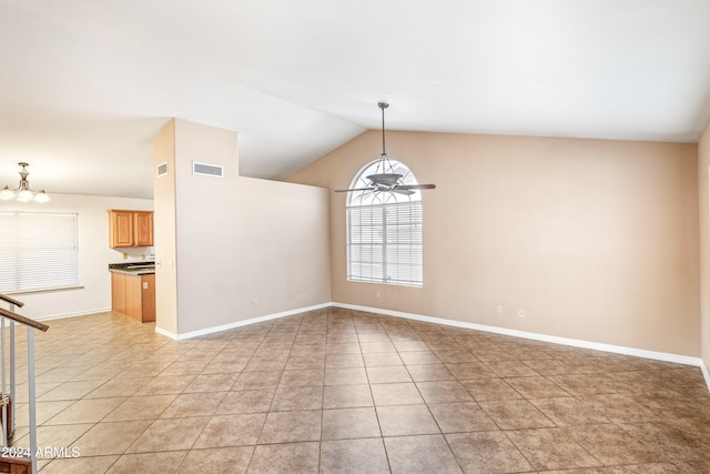 tiled spare room featuring ceiling fan with notable chandelier and vaulted ceiling