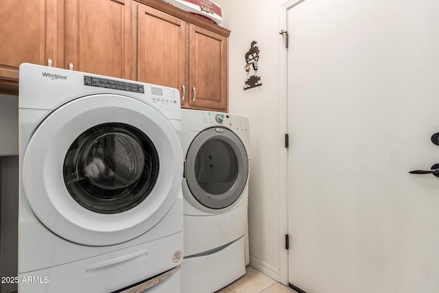 clothes washing area with cabinet space, washing machine and clothes dryer, and light tile patterned floors