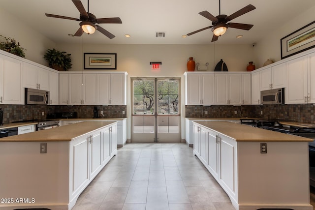 kitchen featuring stainless steel appliances, visible vents, a kitchen island, and white cabinetry