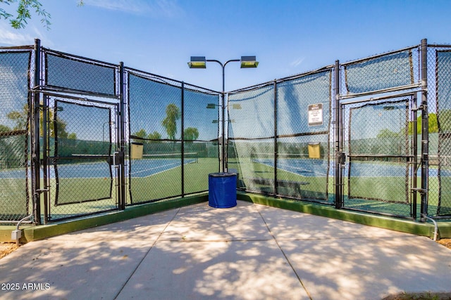 view of tennis court with fence and a gate