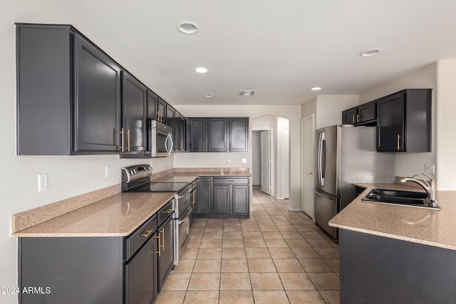 kitchen featuring light stone countertops, sink, light tile patterned floors, and stainless steel appliances