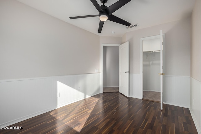 unfurnished bedroom with ceiling fan, dark hardwood / wood-style flooring, a walk in closet, and a closet