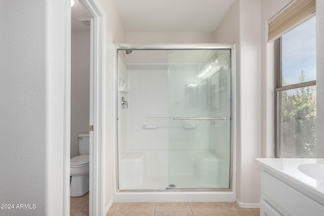 bathroom with toilet, a shower with door, vanity, and tile patterned flooring