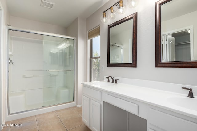 bathroom with tile patterned flooring, vanity, and walk in shower