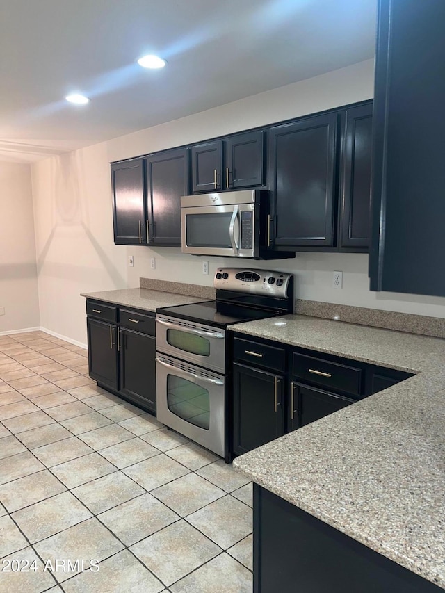 kitchen with light tile patterned floors, light stone countertops, and appliances with stainless steel finishes