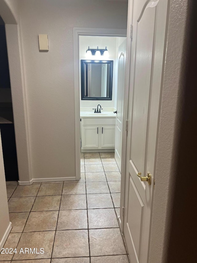 corridor featuring light tile patterned floors and sink