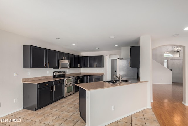 kitchen featuring kitchen peninsula, sink, light hardwood / wood-style flooring, and appliances with stainless steel finishes