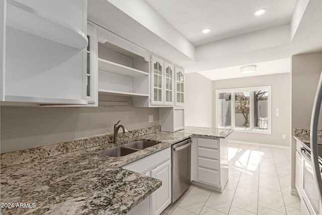 kitchen with light stone countertops, dishwasher, sink, kitchen peninsula, and white cabinets