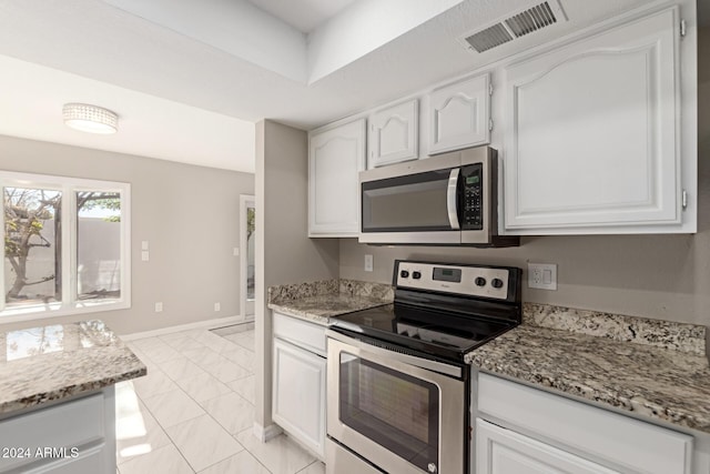 kitchen with light stone counters, white cabinetry, and appliances with stainless steel finishes