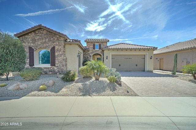 mediterranean / spanish home with driveway, stone siding, a tiled roof, an attached garage, and stucco siding