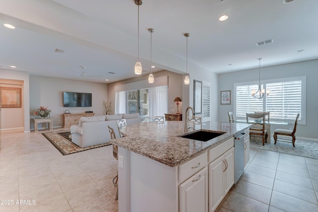 kitchen with visible vents, stainless steel dishwasher, white cabinetry, a sink, and an island with sink