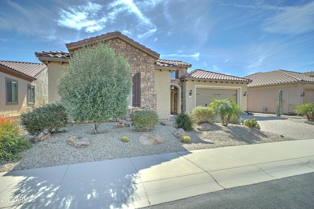 mediterranean / spanish house featuring a garage, stone siding, driveway, and stucco siding