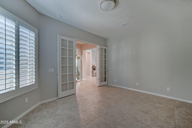 empty room featuring light tile patterned floors, french doors, visible vents, and baseboards