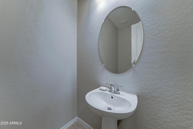 bathroom featuring a textured wall and a sink