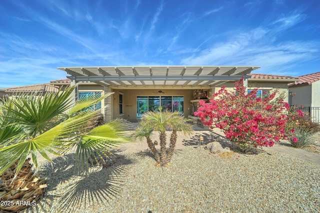 rear view of house featuring a tiled roof, ceiling fan, and stucco siding