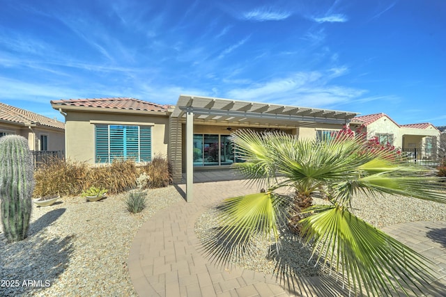 rear view of house with a patio, stucco siding, fence, a pergola, and a tiled roof