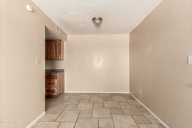 spare room featuring baseboards, a textured ceiling, visible vents, and light tile patterned floors