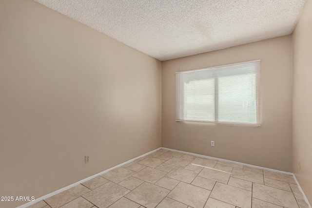 unfurnished room featuring light tile patterned flooring, baseboards, and a textured ceiling