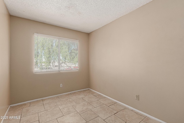 empty room with baseboards, light tile patterned floors, and a textured ceiling